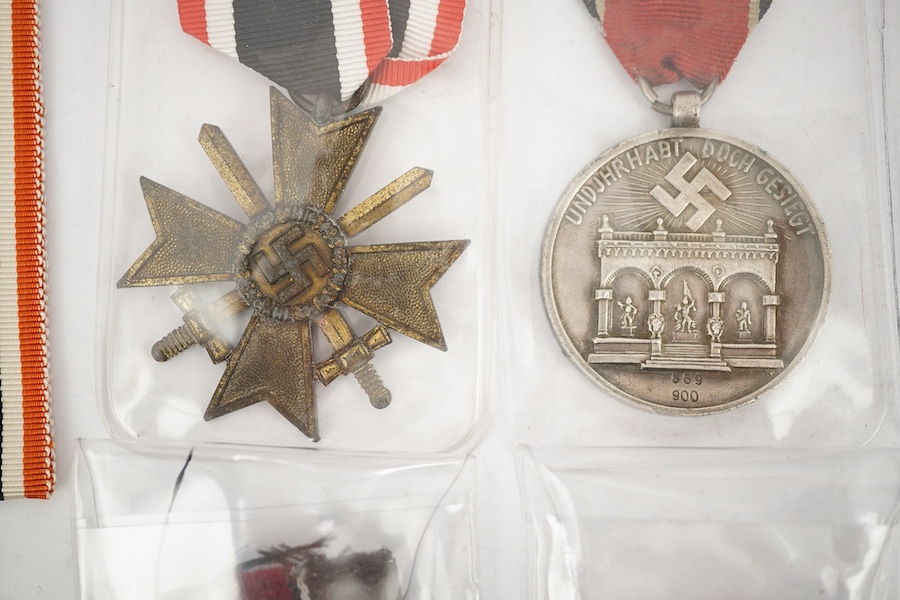 Nine German WWII medals; three Blood Order medals, a Second class Iron Cross, a War Merit medal in its original envelope, plus another unpacketed, a Second class War Merit cross, an Eastern Front Medal, and a West Wall M